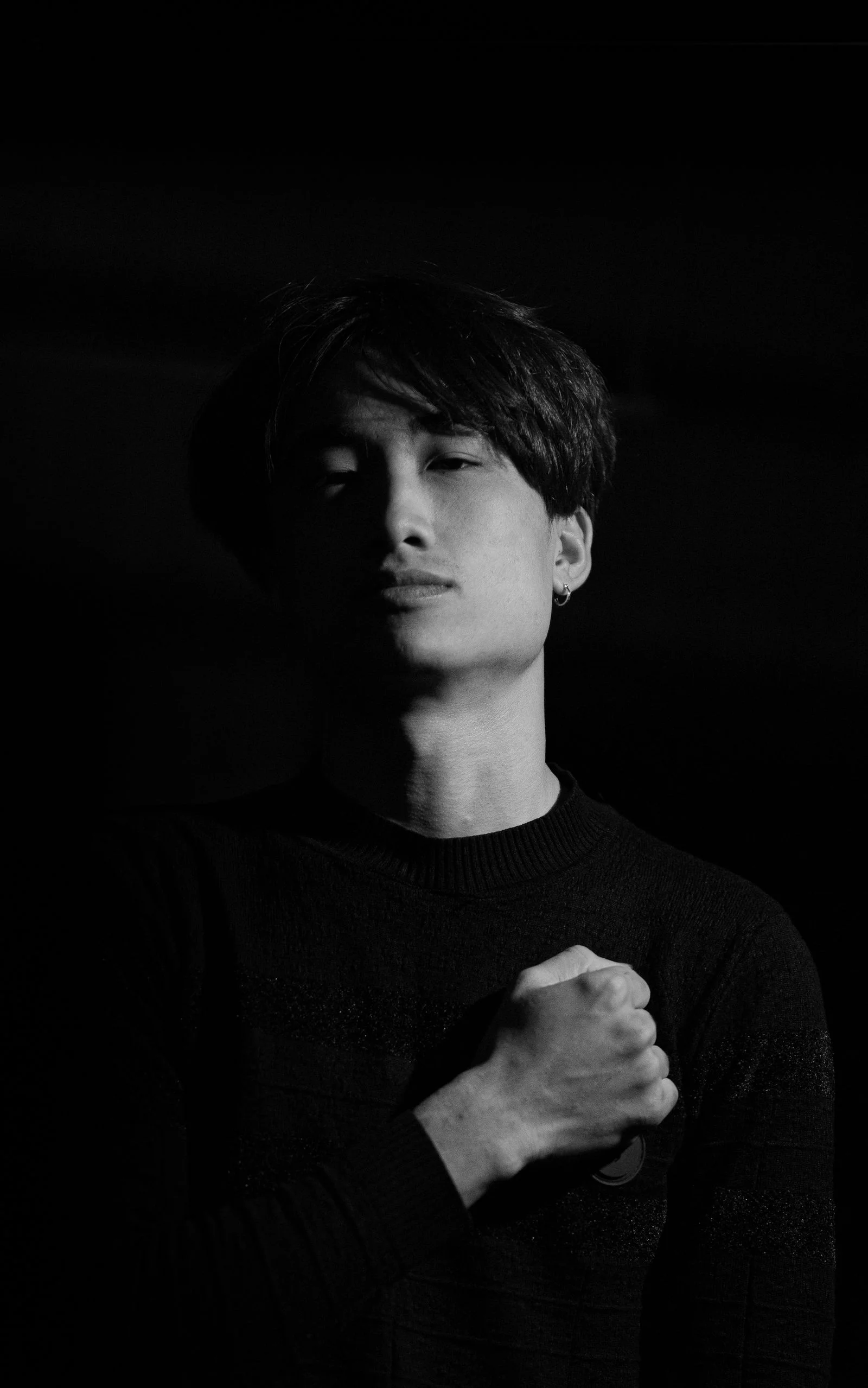 Black and white portrait of a confident man with hand on chest, showcasing emotion.